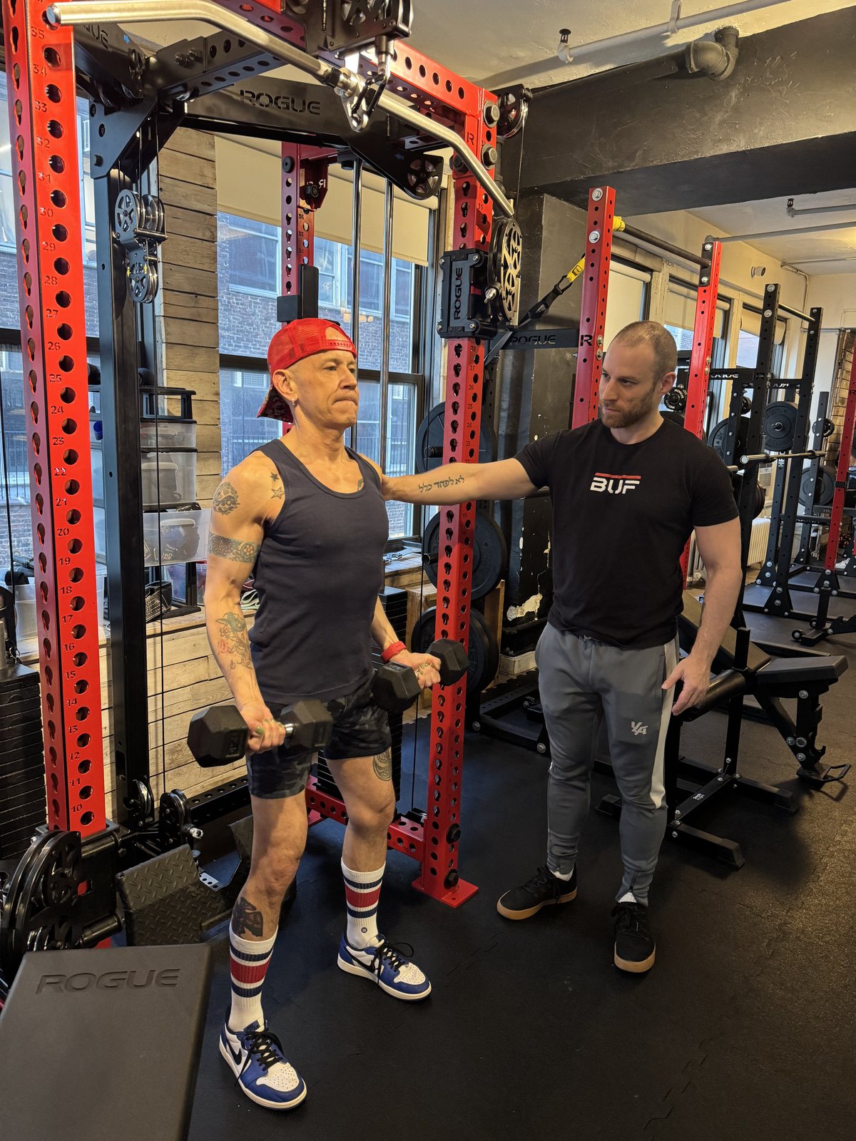 Senior personal training NYC — BUF coach guiding an older client through a dumbbell curl at the Midtown Manhattan studio